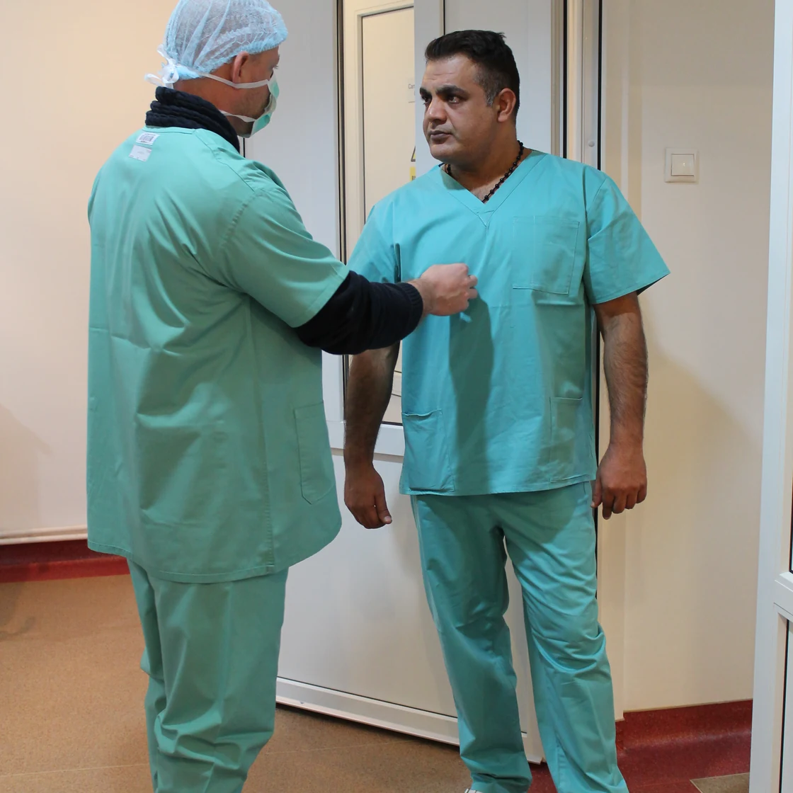 Doi chirurgi se pregătesc pentru operație, pe coridorul blocului operator
