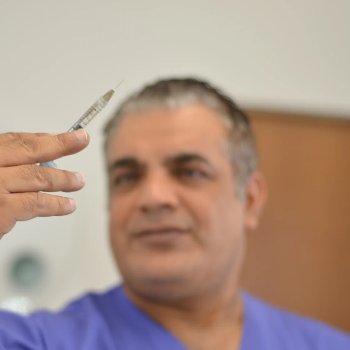 Dr. Rachad, zâmbind, cu un bisturiu în mână, în clinica Art Estetica