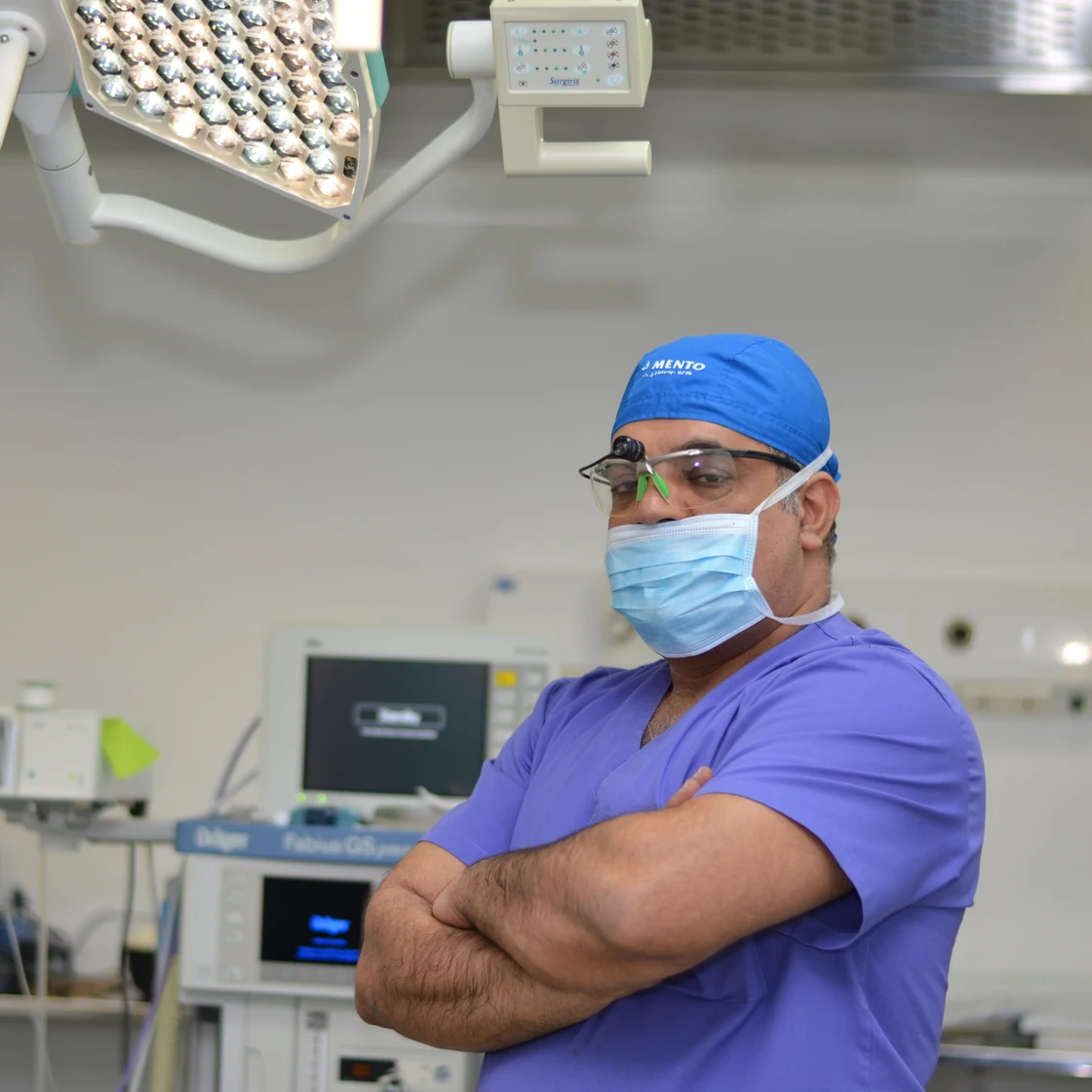 Chirurgul, în sala de operație, cu brațele încrucișate, înaintea unei reducții mamare